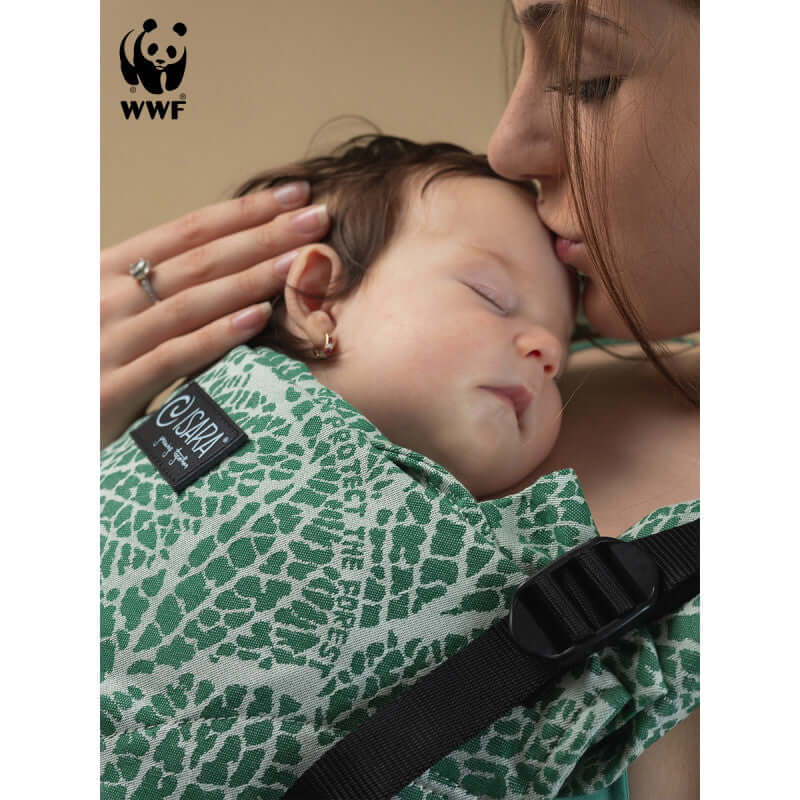 Isara The One - Majestic Green Forest baby carrier in use by a parent cuddling their sleeping baby | Babymaxi