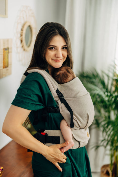 LennyLight baby carrier in Peanut Butter color, featuring a parent holding a baby comfortably in a home setting.
