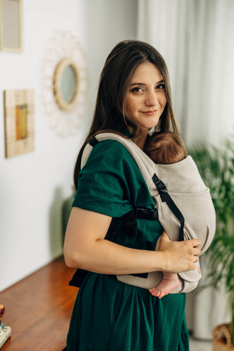 Mom in green dress using LennyLight baby carrier in Peanut Butter color, comfortably carrying her baby.