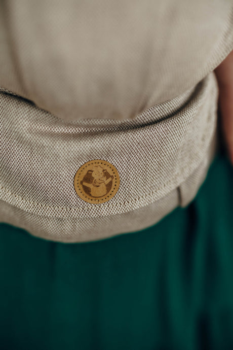 Close-up of the LennyLight baby carrier in peanut butter color, featuring a stylish logo badge.