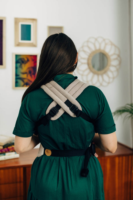 LennyLight baby carrier in Peanut Butter color, worn by a woman, showcasing adjustable straps from the back.