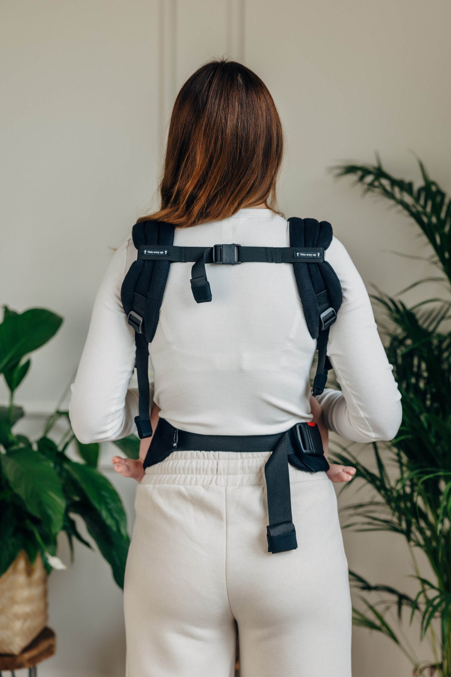 Back view of a person wearing the LennyLight black baby carrier, showcasing adjustable straps and minimalistic design.