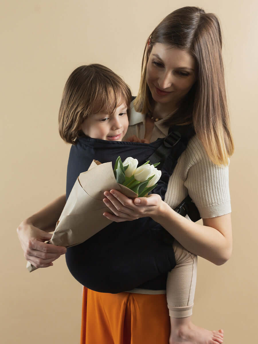 Isara Preschooler (up to 30kg) - Noire baby carrier shown with a child holding flowers | Babymaxi