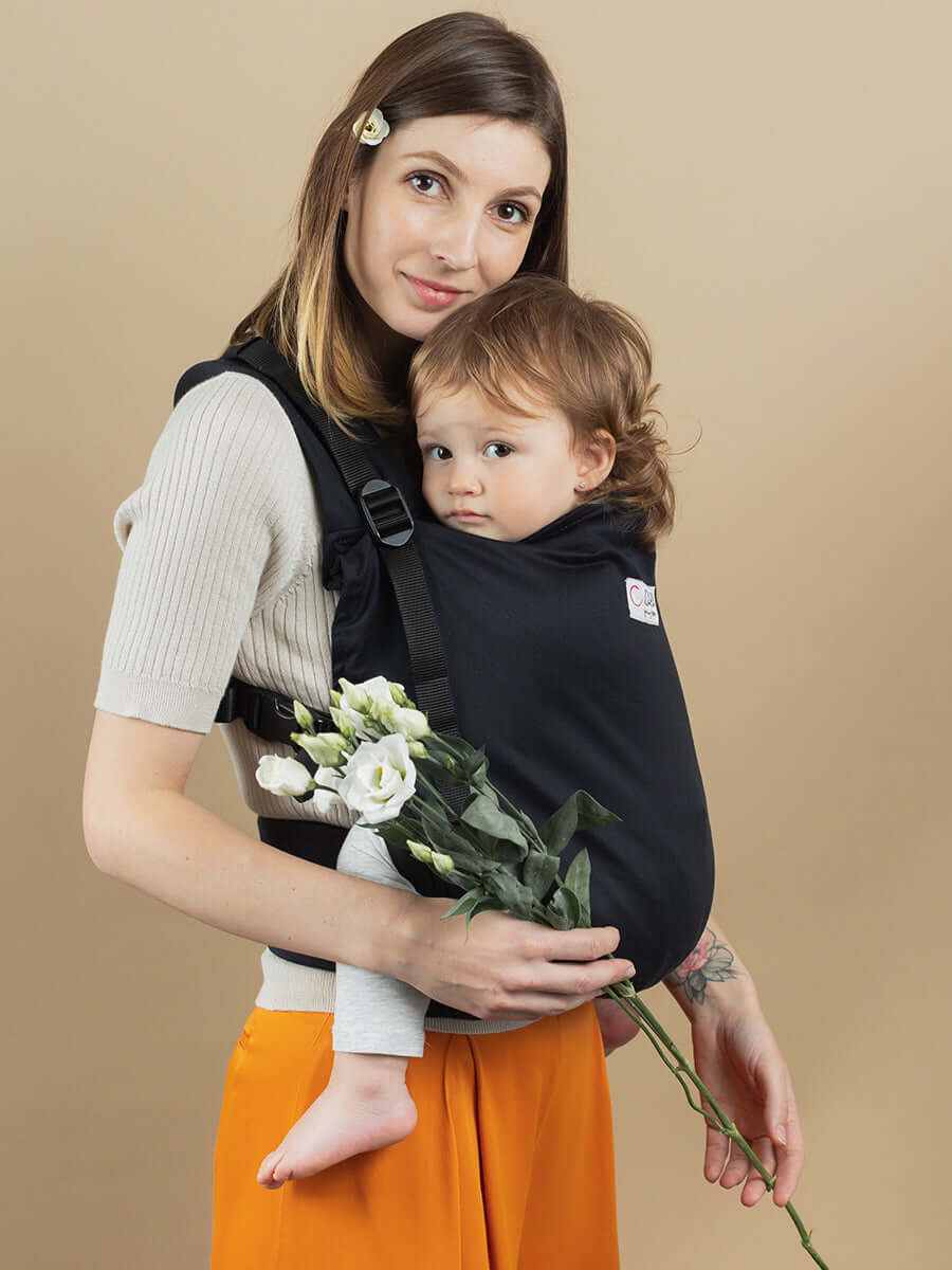 Woman using Isara Preschooler (up to 30kg) - Noire baby carrier with flowers | Babymaxi