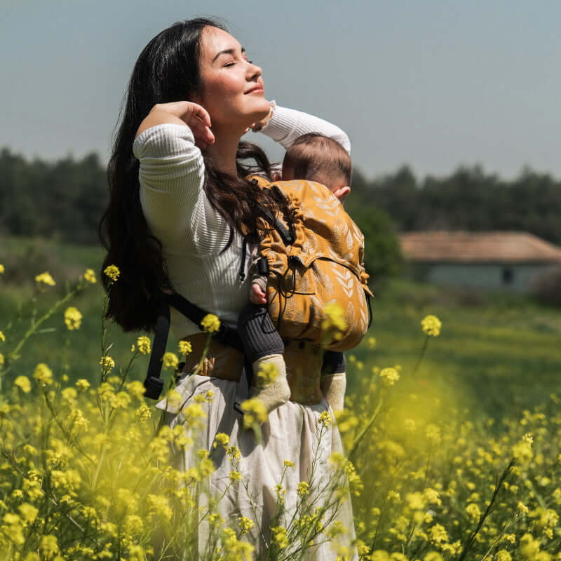Neko Switch Baby Size - Alinda carrier with baby in ergonomic position in a field of flowers | Babymaxi