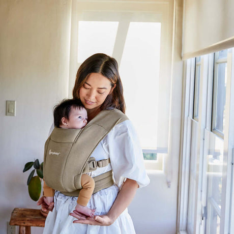 Mom using Ergobaby Embrace - Soft Olive baby carrier with newborn comfortably in front | Babymaxi