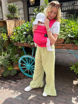 Woman wearing Nomad Air Roar baby carrier in pink tiger print with infant in outdoor garden setting
