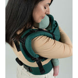 A mother carries her baby comfortably in the Isara The One - Evergreen Linen carrier, showcasing adjustable features | Babymaxi