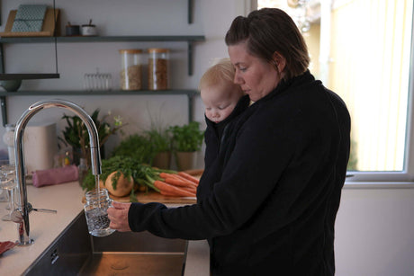 Mamalila Basel Baby Carrier Fleece Jacket – Black being used at home by a parent with a baby, cozy warm and practical | Babymaxi