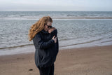 Mom wearing Mamalila Softshell Babywearing Jacket Allrounder - Navy while holding baby on the beach | Babymaxi