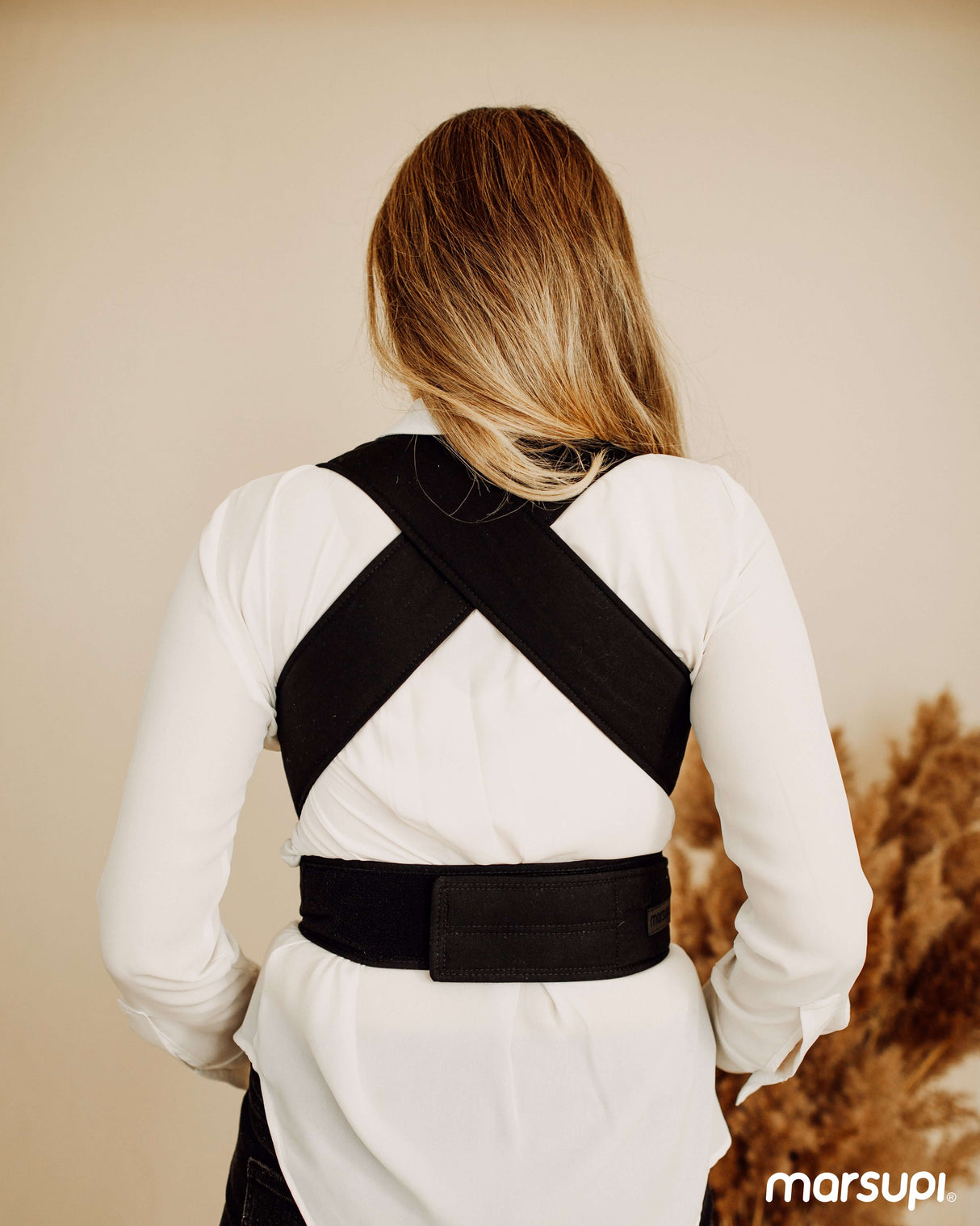 A parent wearing the Marsupi Classic - Black baby carrier, showcasing the ergonomic cross straps for comfort | Babymaxi