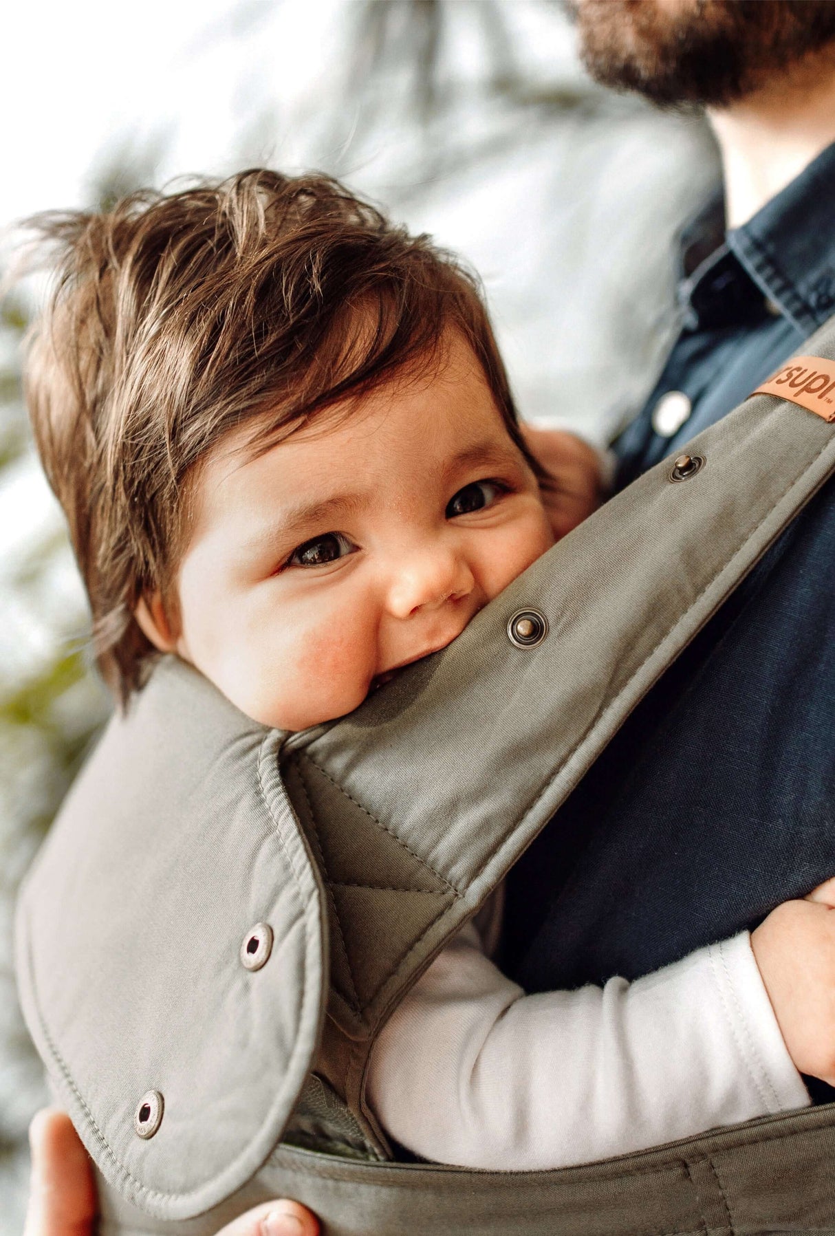 Happy baby comfortably nestled in Marsupi Classic - Olive baby carrier, highlighting ergonomic design | Babymaxi