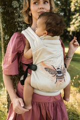 Woman demonstrating comfort while wearing Nomad Air Hexa Bee baby carrier with infant