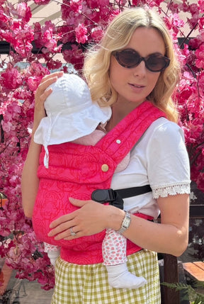 Close-up of mother and baby bonding while wearing Nomad Air Roar carrier among cherry blossoms