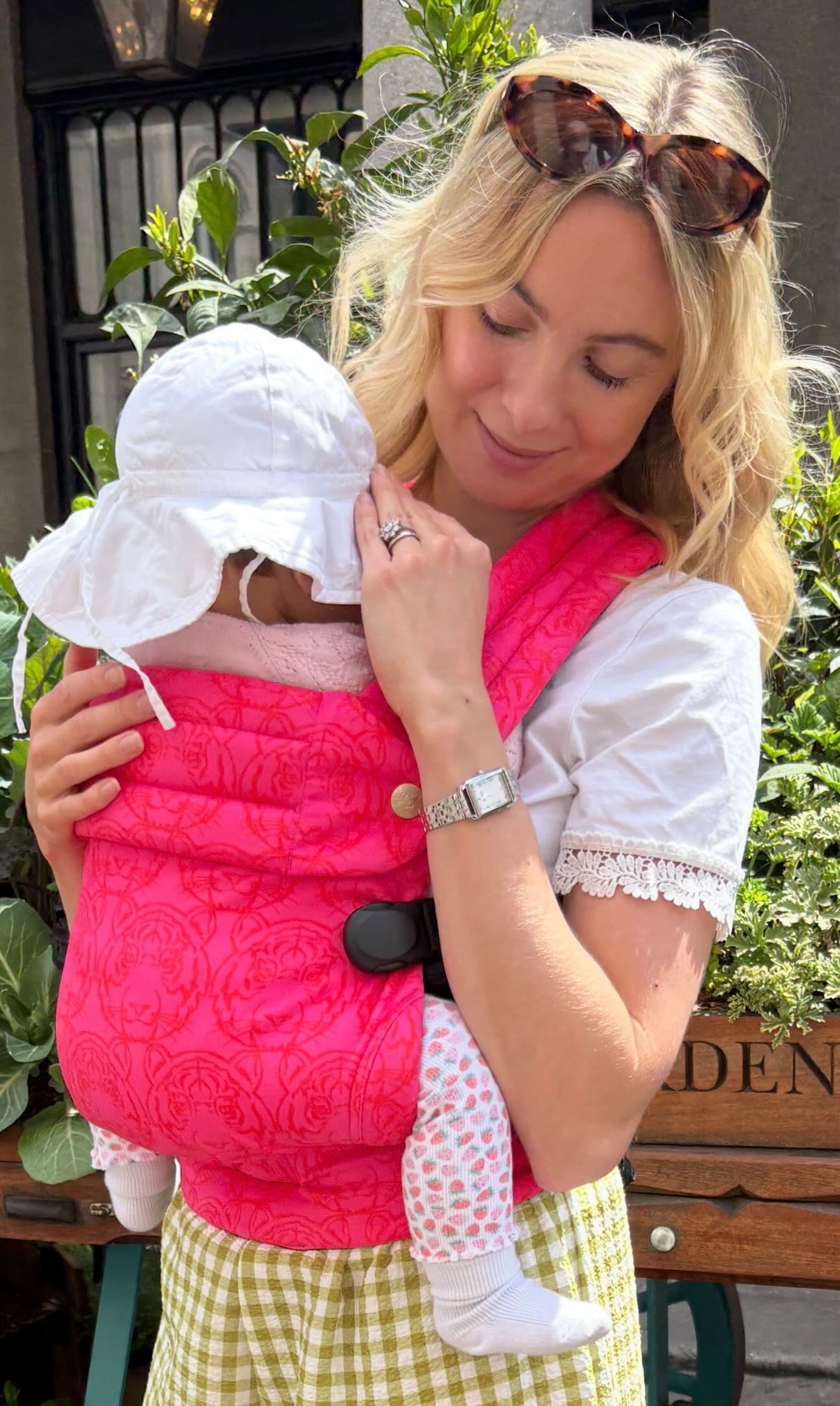 Mother holding infant close in Nomad Air Roar baby carrier in urban garden setting