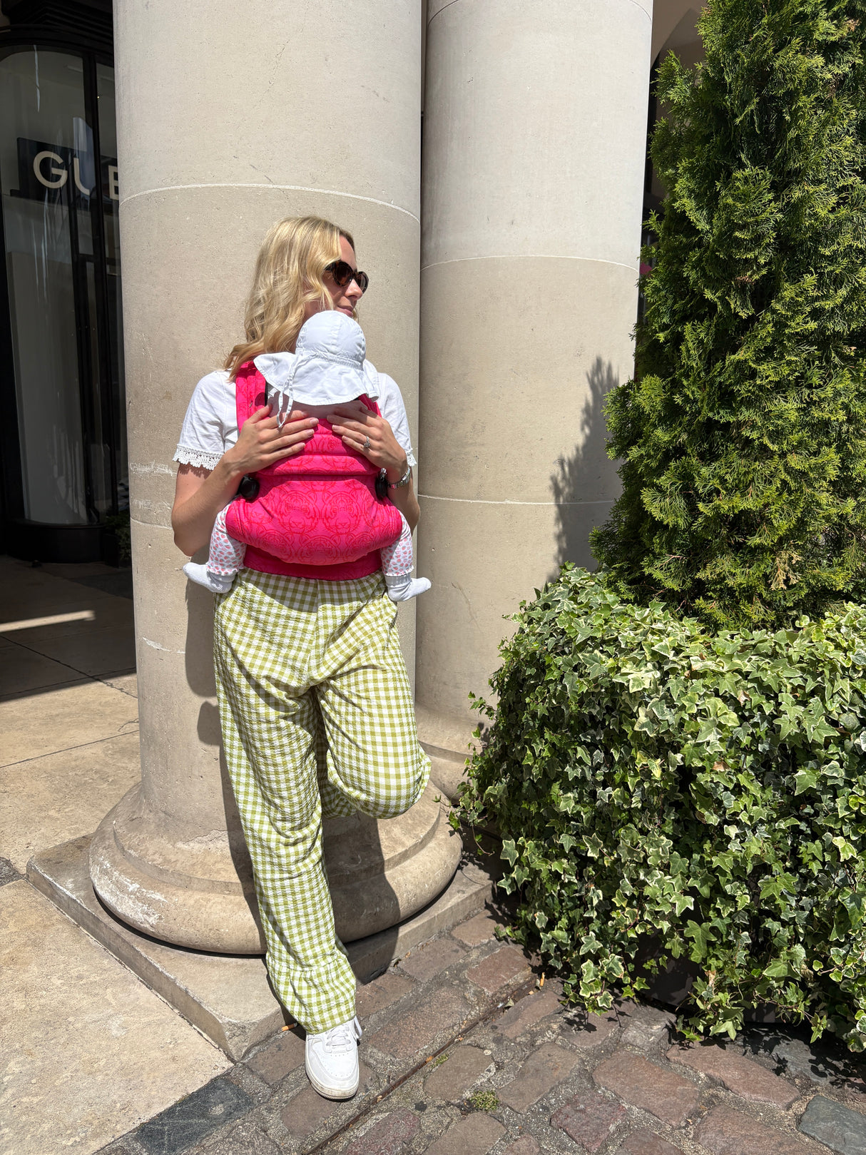 Back view of woman wearing Nomad Air Roar carrier with baby against architectural column backdrop