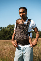 Female parent wearing Nomad Air jaguar carrier hands-free while carrying baby outdoors