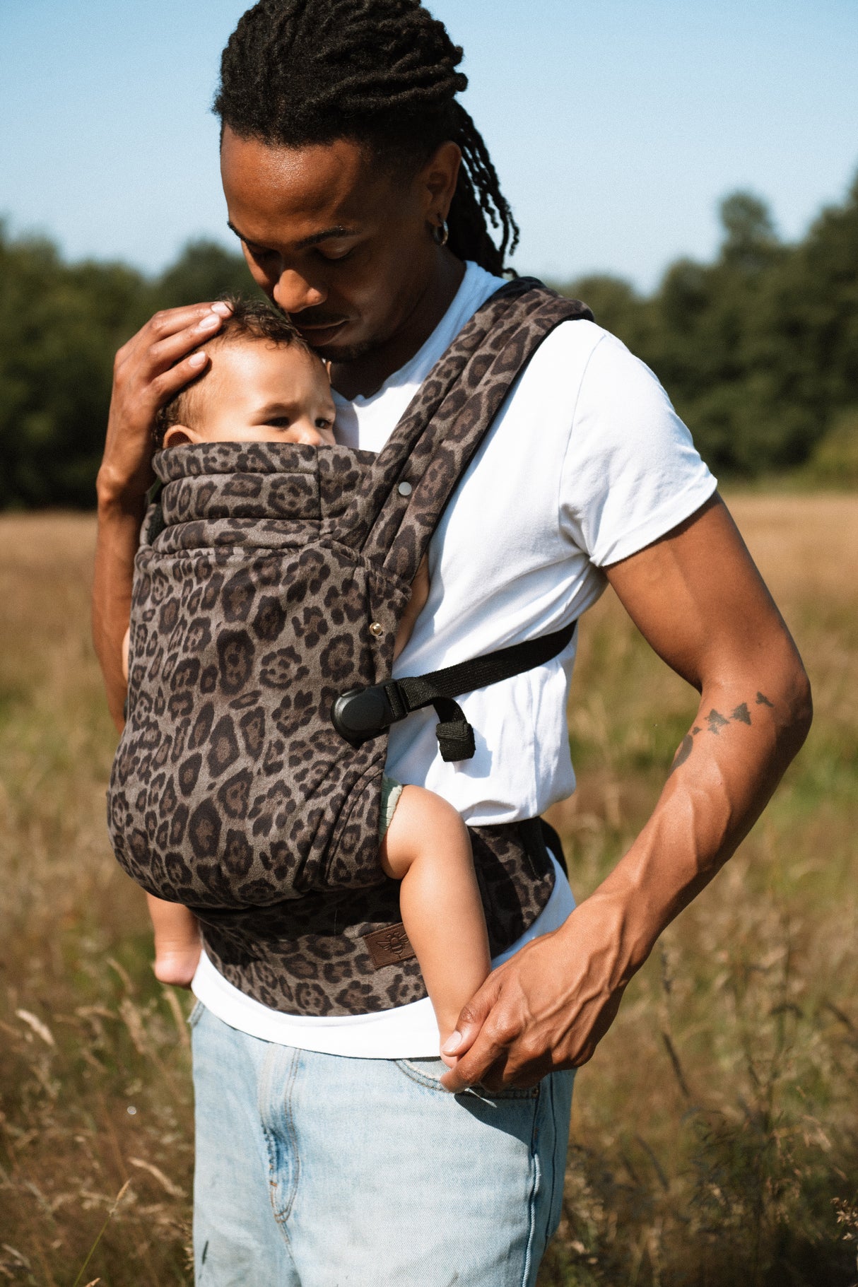 Father wearing Nomad Air jaguar carrier with infant, showing product versatility for male wearers