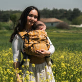Mom with baby in Neko Switch Baby Size - Alinda carrier, enjoying nature in a field of flowers | Babymaxi