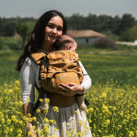 Mom with baby in Neko Switch Baby Size - Alinda carrier, enjoying nature in a field of flowers | Babymaxi