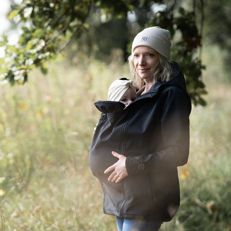 Mamalila Softshell Babywearing Jacket Allrounder Fit Black, mother carrying baby on front outdoors