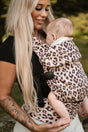 Mother smiling down at baby wearing Nomad Air Dusky Leopard baby carrier with blush leopard print